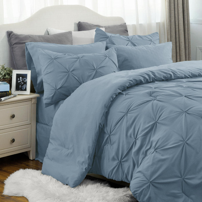 Blue textured bedding set on a bed with pillows and a nightstand.