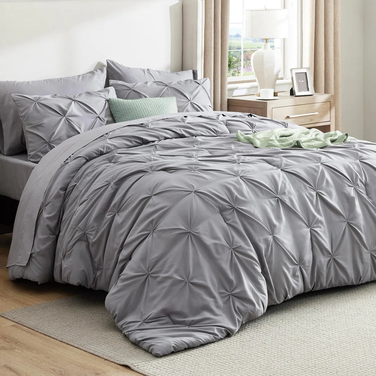 Gray textured comforter set on a bed in a bedroom with light decor.
