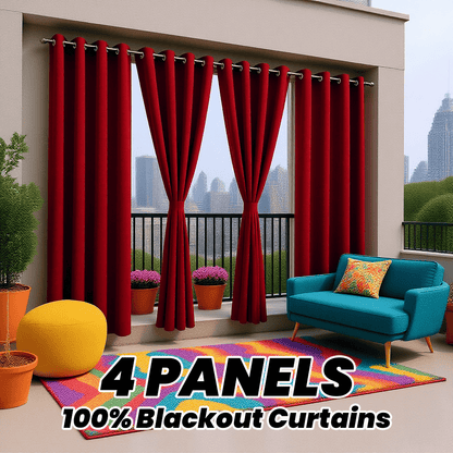 Red outdoor curtains with a blue sofa and colorful rug on a balcony with cityscape view.
