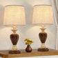 Two ornate table lamps with brown and gold bases on a wooden surface.
