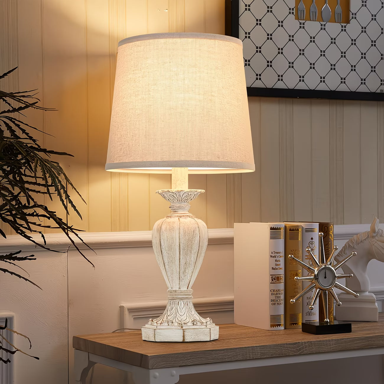Decorative table lamp on a wooden surface with books and a plant in the background