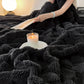 Person reading a book on a black blanket with a lit candle beside them.