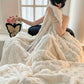 Person wrapped in a fluffy white blanket in a cozy room.