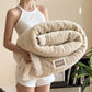 Person holding a beige textured blanket with a brand label in a home setting