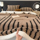 Bed with patterned brown blanket and pillows in a bedroom setting