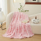 Pink blanket draped over a white sofa in a cozy living room setting.