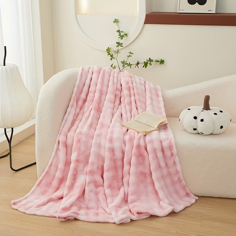 Pink blanket draped over a white sofa in a cozy living room setting.