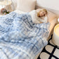 Woman lying on a bed under a blue and white patterned blanket in a cozy room.