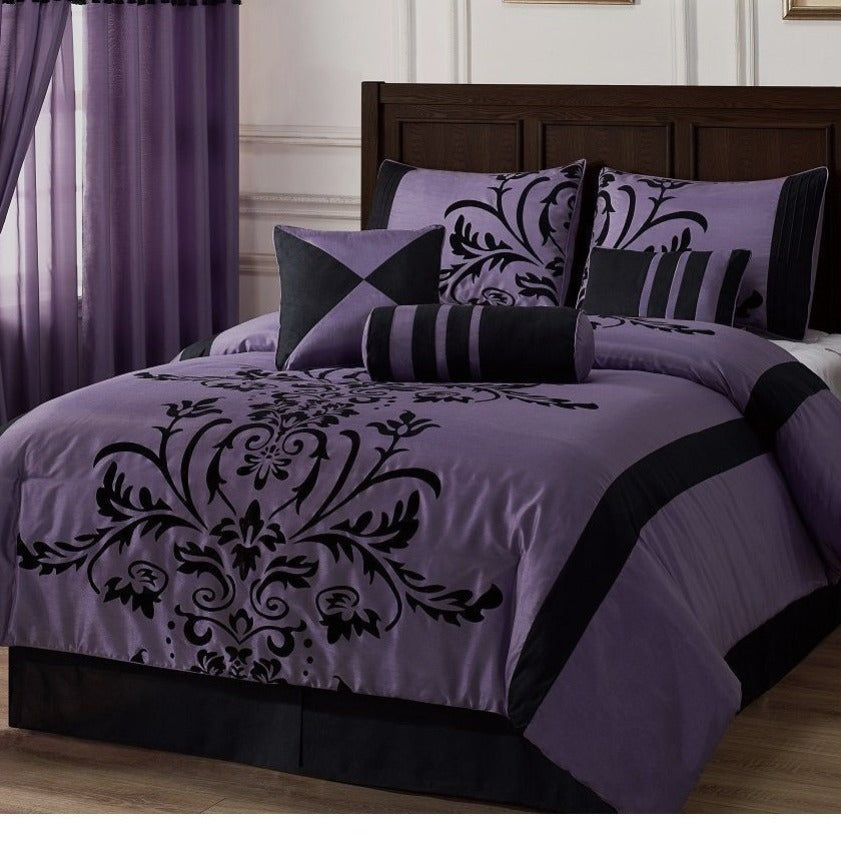 Purple and black damask patterned bedding set on a bed in a bedroom.