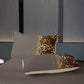 Gray bedding set with leopard print accent pillows on a bed against a striped wall.