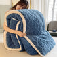 Person hugging a large blue textured blanket indoors.