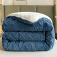 Folded blue textured blanket on a bed with a neutral headboard.