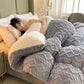 Woman lying on a bed under a gray textured blanket and pillow