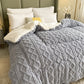Gray textured comforter on a bed with white pillows in a bedroom setting.