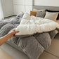 Person adjusting a white pillow on a bed with gray comforter