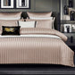 Neatly made bed with striped bedding and decorative pillows in a bedroom setting.