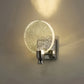 Wall-mounted light fixture with a round, starry glass shade on a neutral background