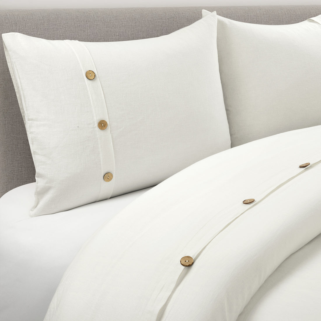 Beige pillows and duvet with button details on a neutral background