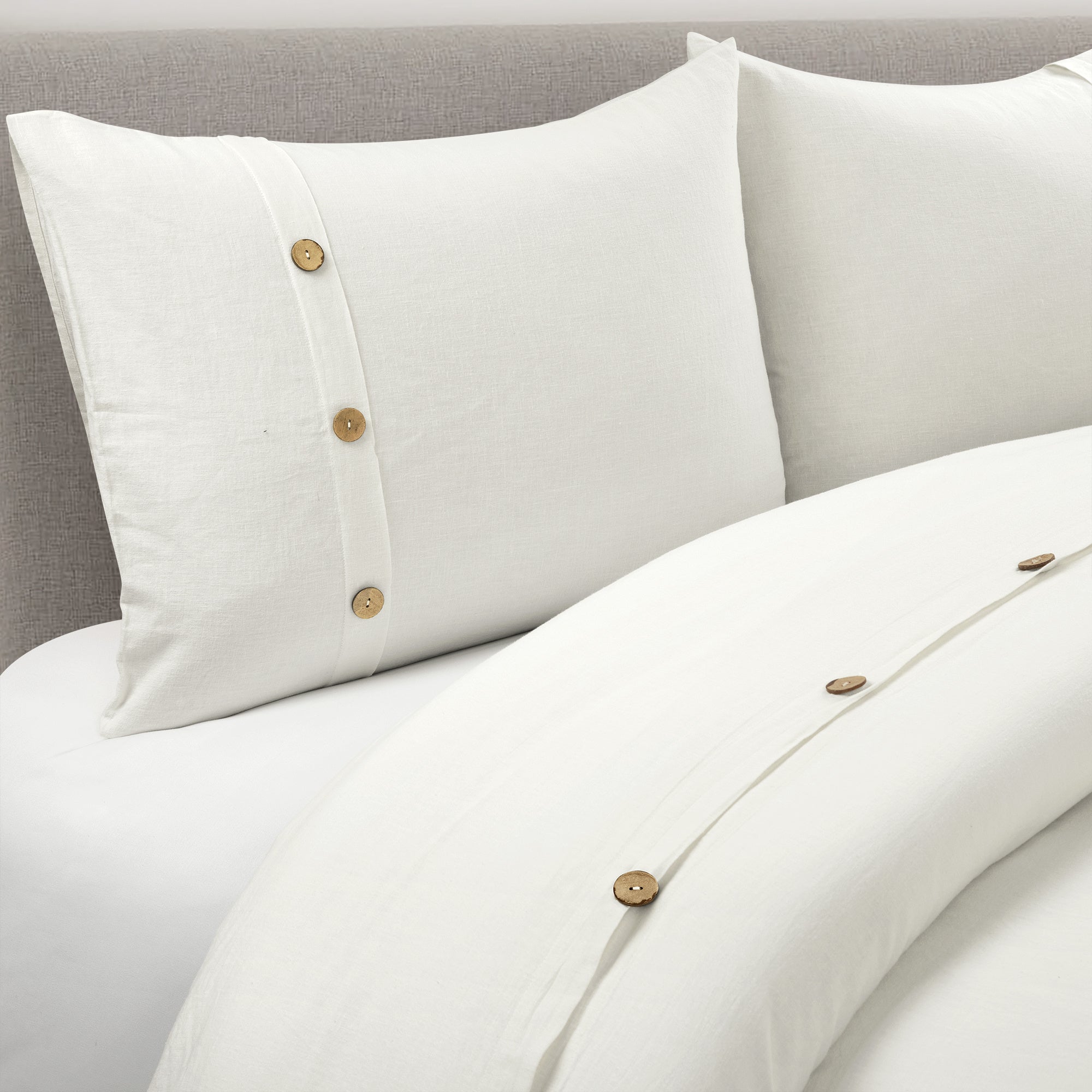 Beige pillows and duvet with button details on a neutral background